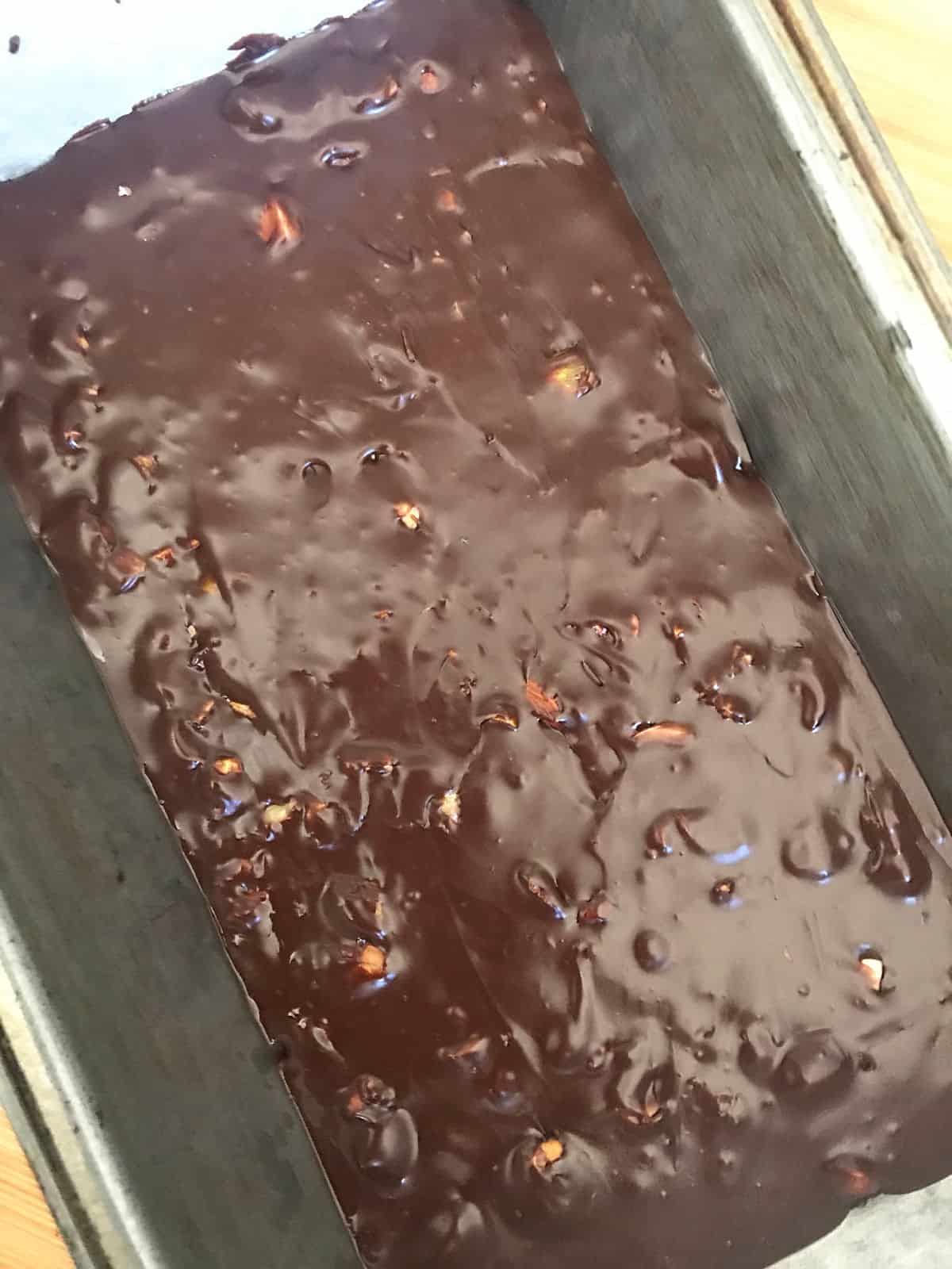 Metal loaf pan with dark chocolate fudge mixture.