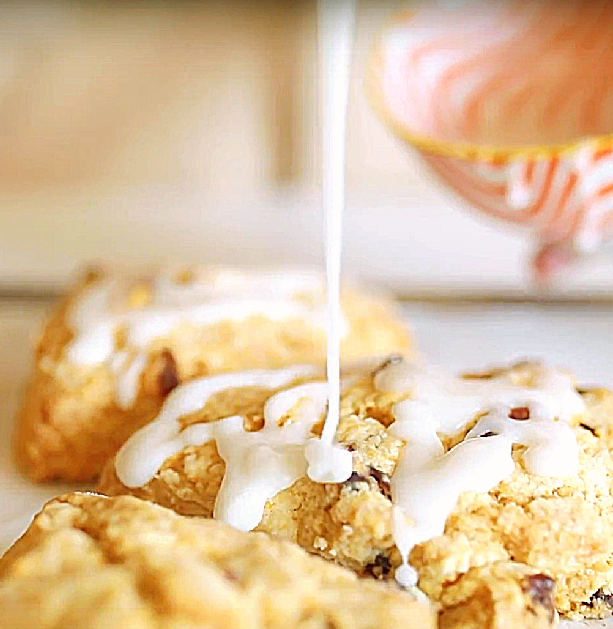 Glazing baked scones from an orange white bowl.