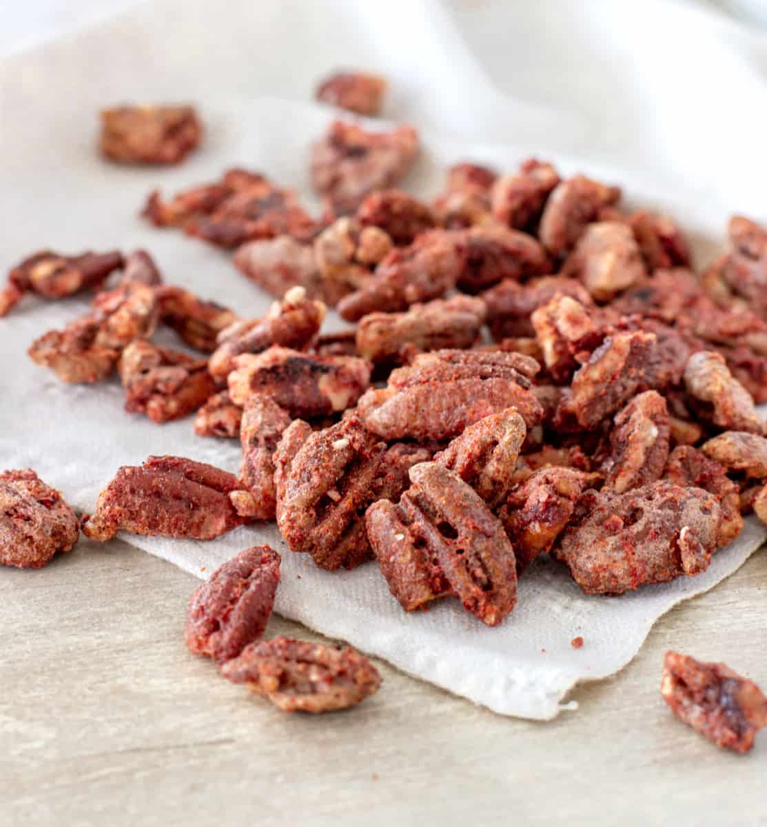 Bunch of cocktail pecans on white napkin.