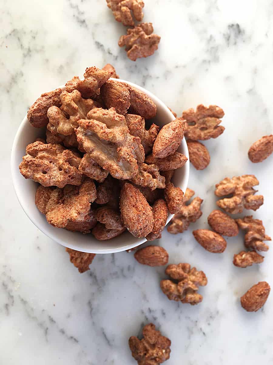 Cocktail nuts in white bowl on white marble.