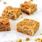 Four blondie squares on white marble surface.