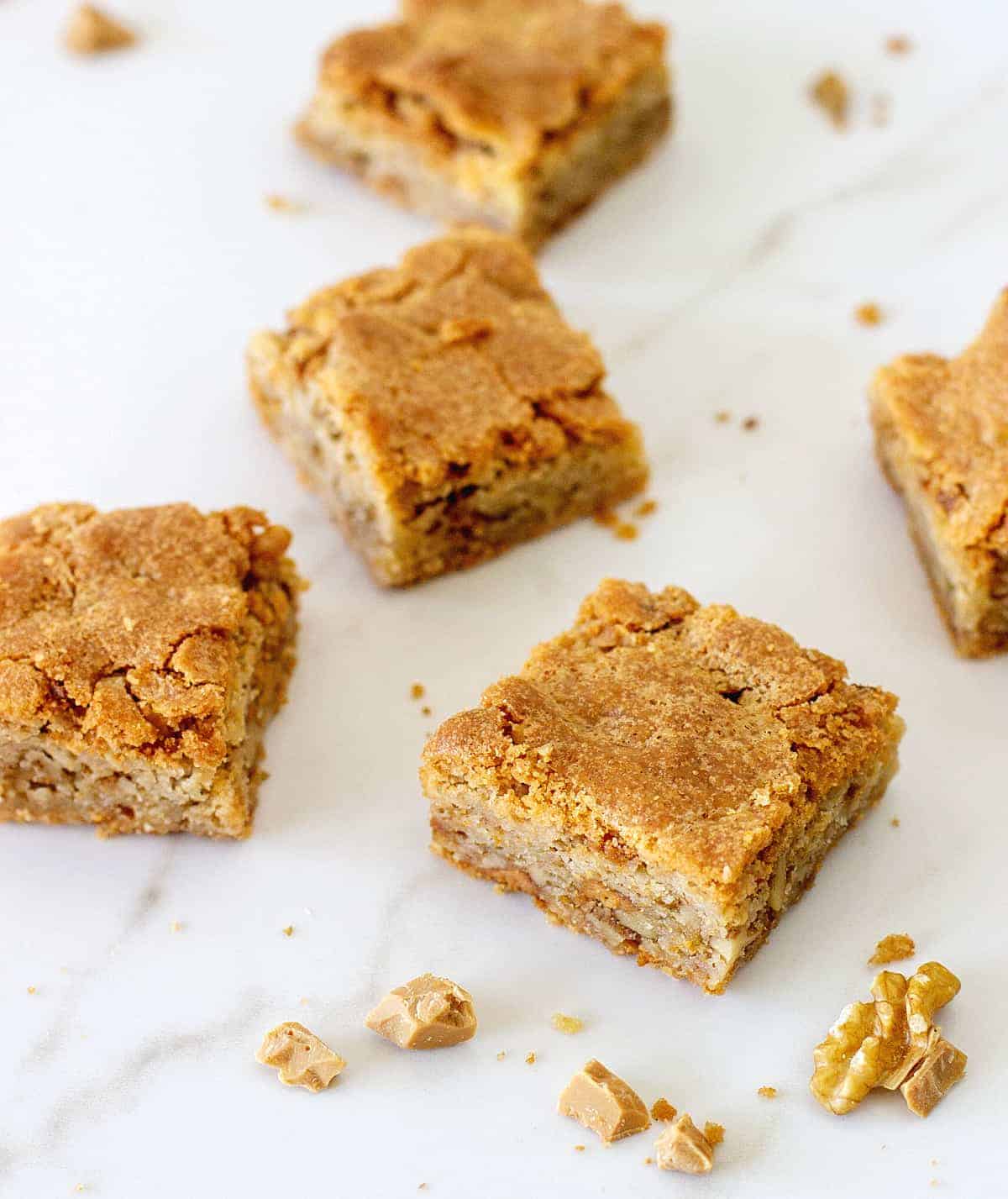 Walnut blondie squares on white marble surface.