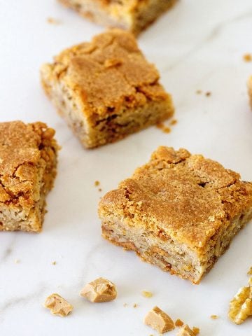 Several blondie squares on a white marbled surface.