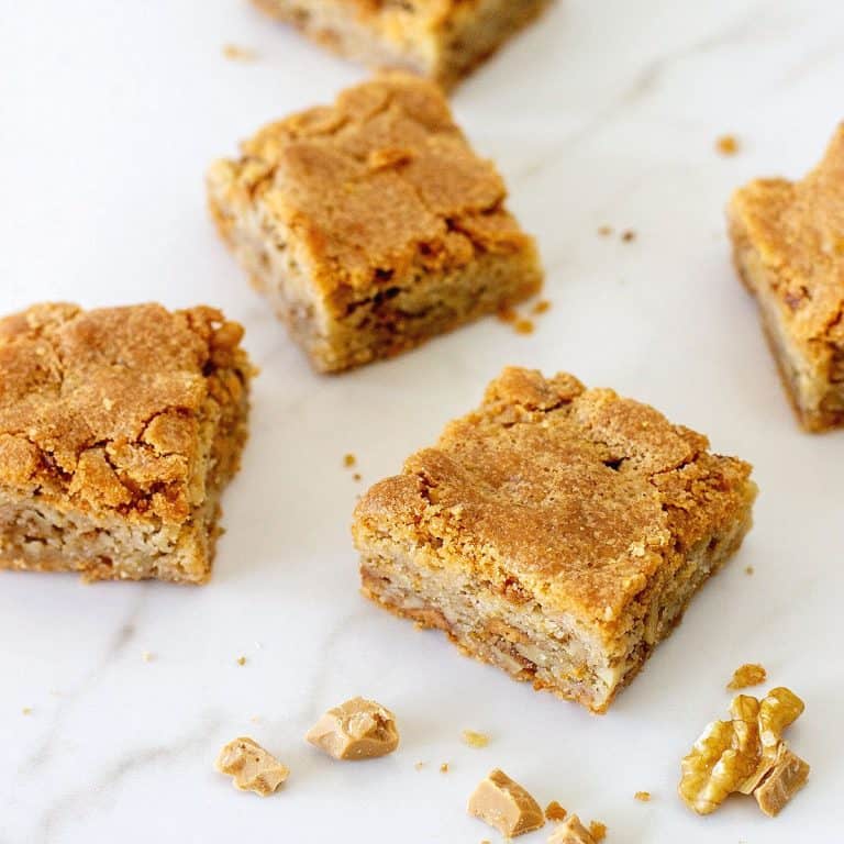 Several blondie squares on a white marbled surface.