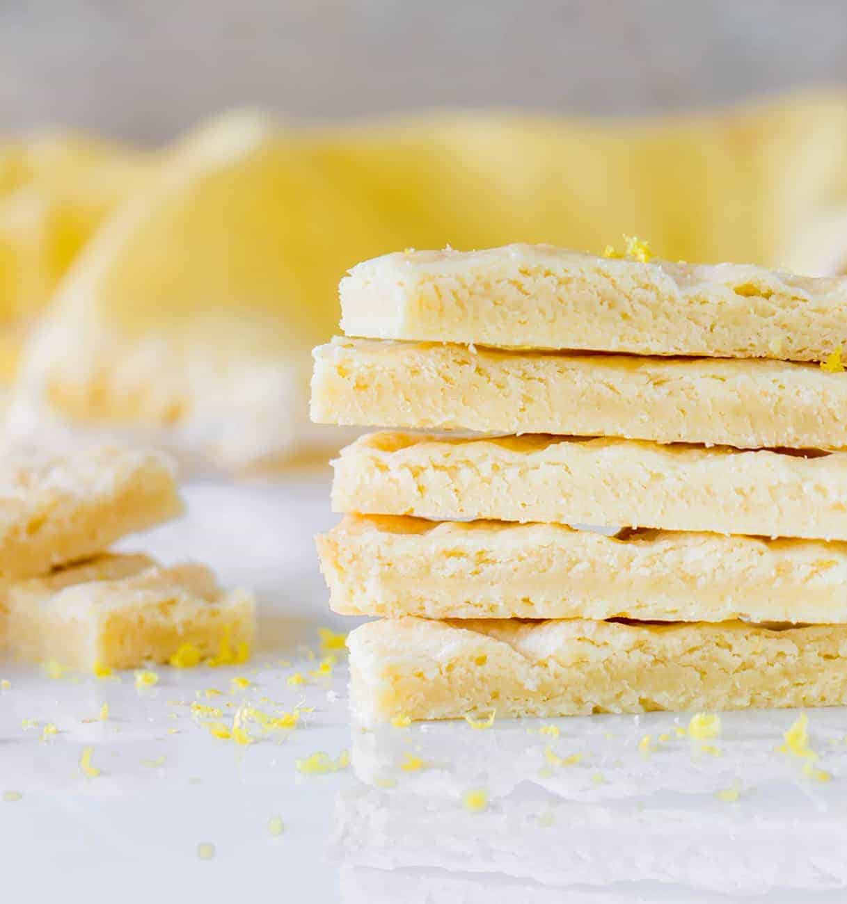 Shortbread fingers stacked on a white surface and yellow background. 