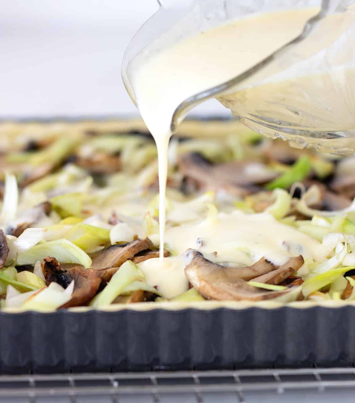 Pouring binding cream on mushroom quiche