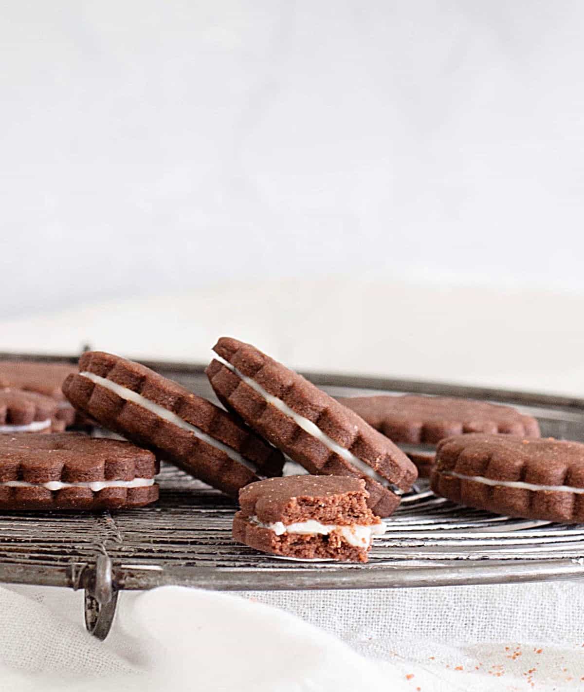 Chocolate sandwich cookies on wire rack, grey white background.