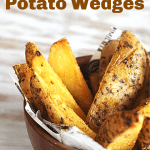 Baked potato wedges in wooden bowl on white surface, image with text