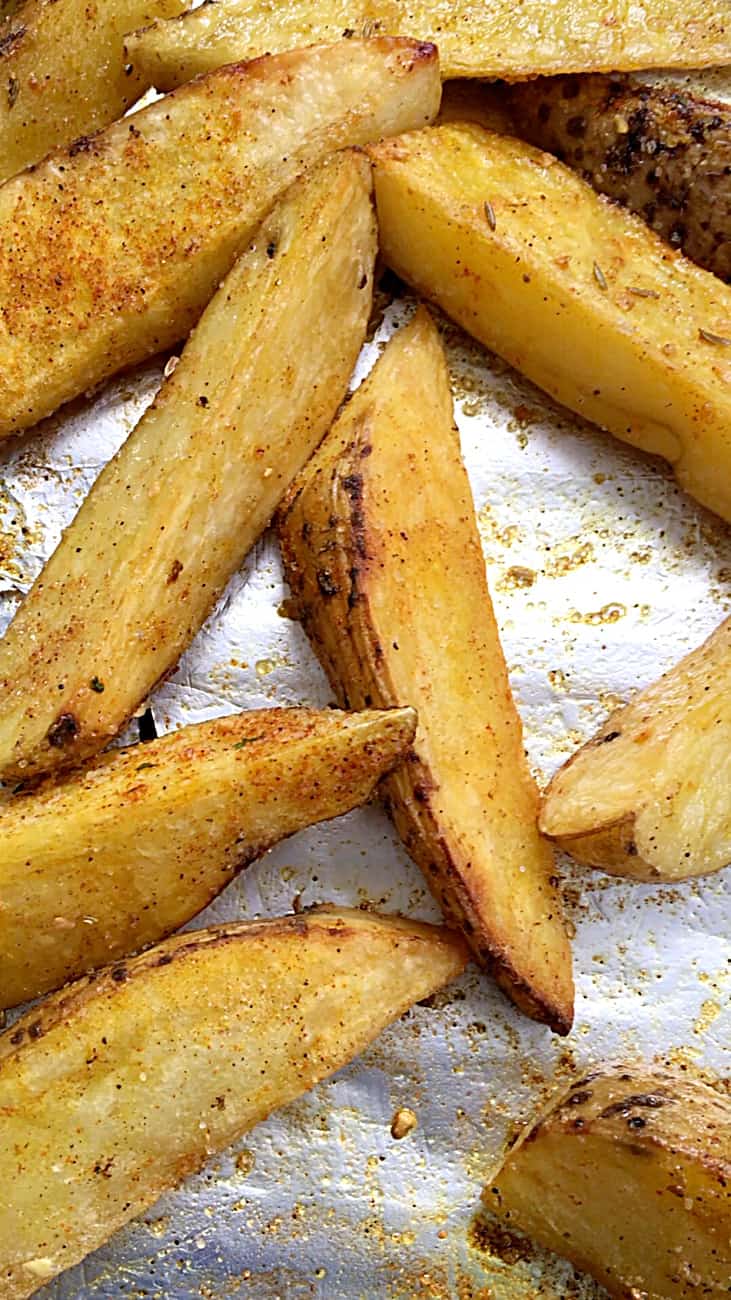 Baked spiced unpeeled potato wedges on aluminum paper