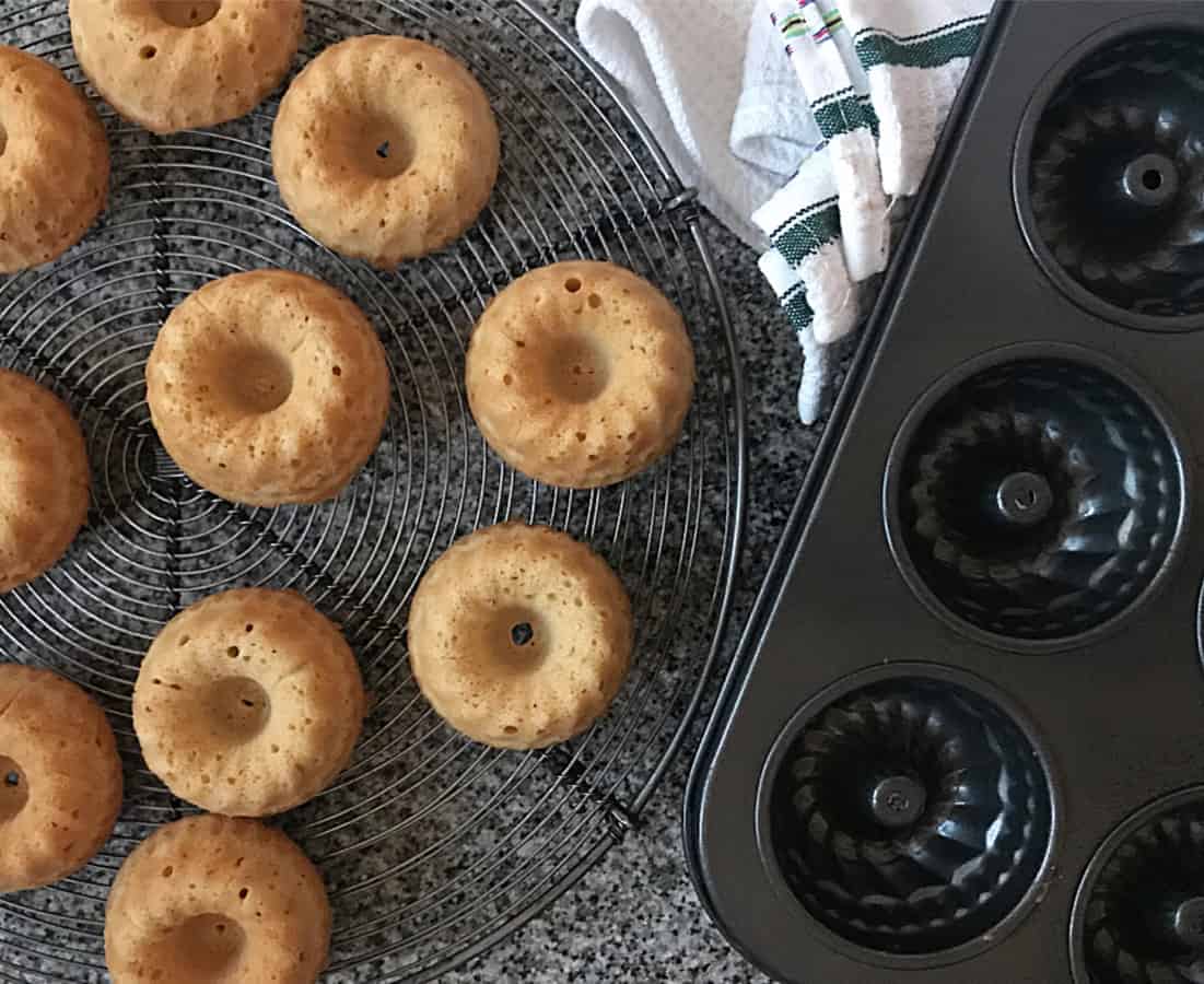 Baked mini cakes on wire rack, black metal mini bundt cake pan, kitchen towel