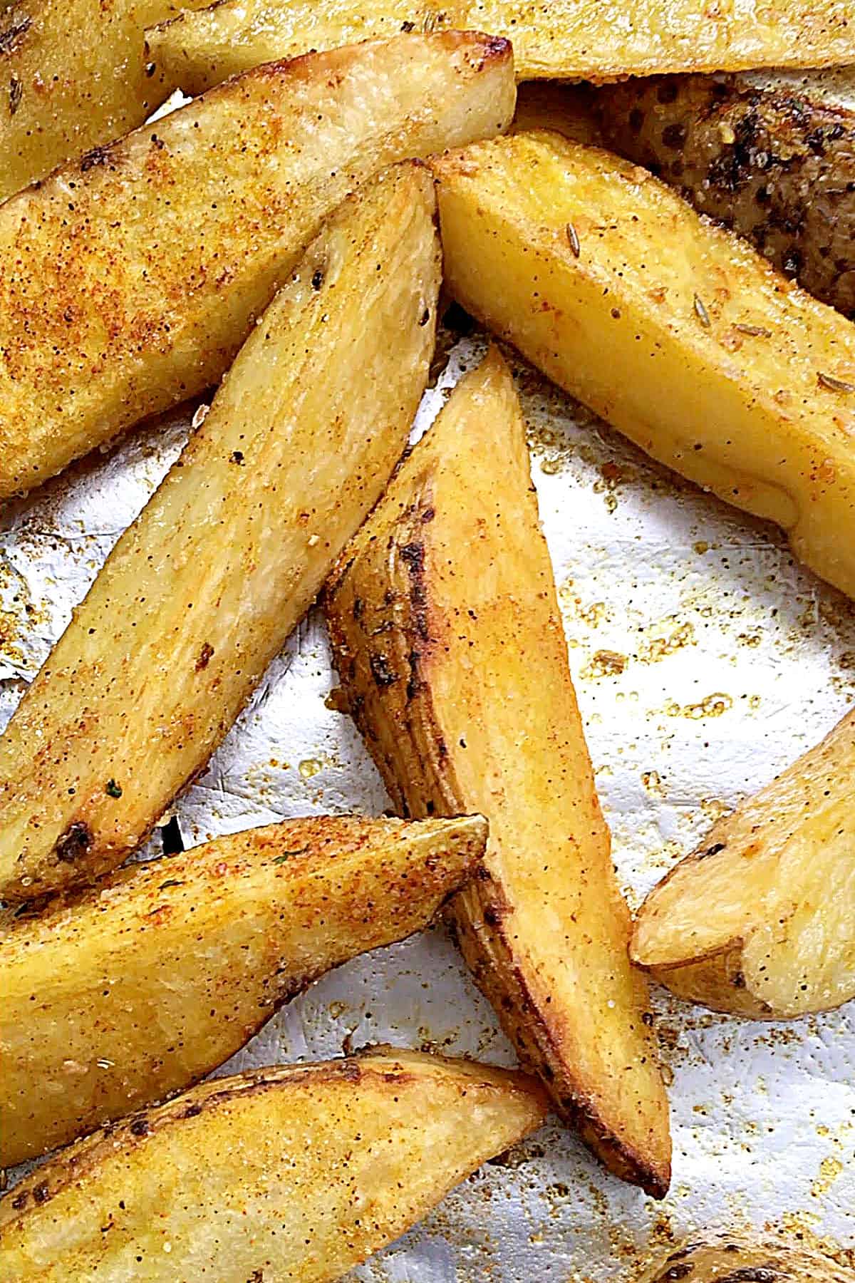 Aluminum foil with spice-rubbed baked potato wedges.