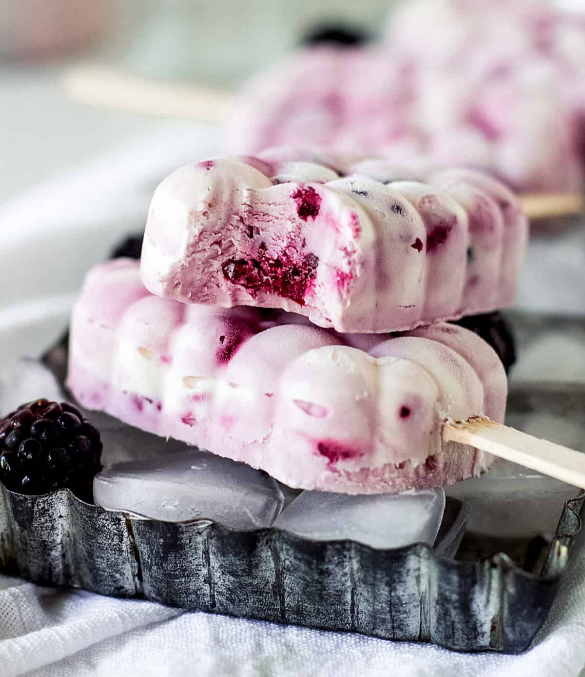 Close-up of bitten Purple and white Ice cream popsicles on a metal long pan.