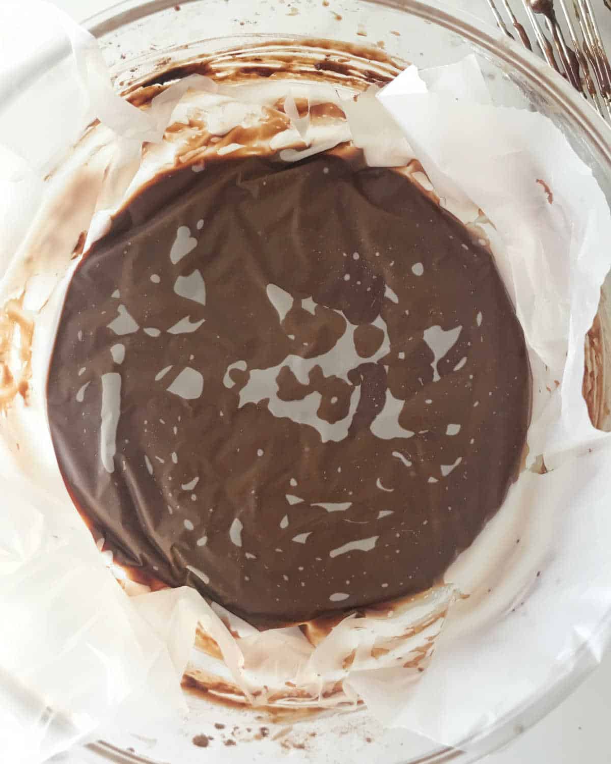 Plastic sheet covering chocolate pudding mixture in a glass bowl.
