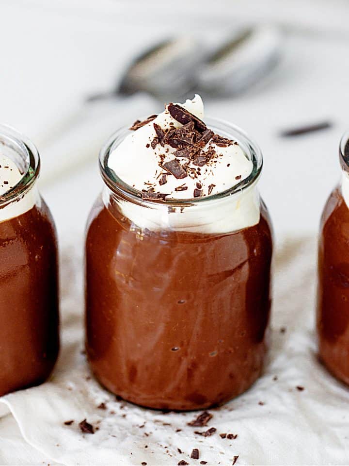 Glass jars with chocolate pudding and crem, grey background