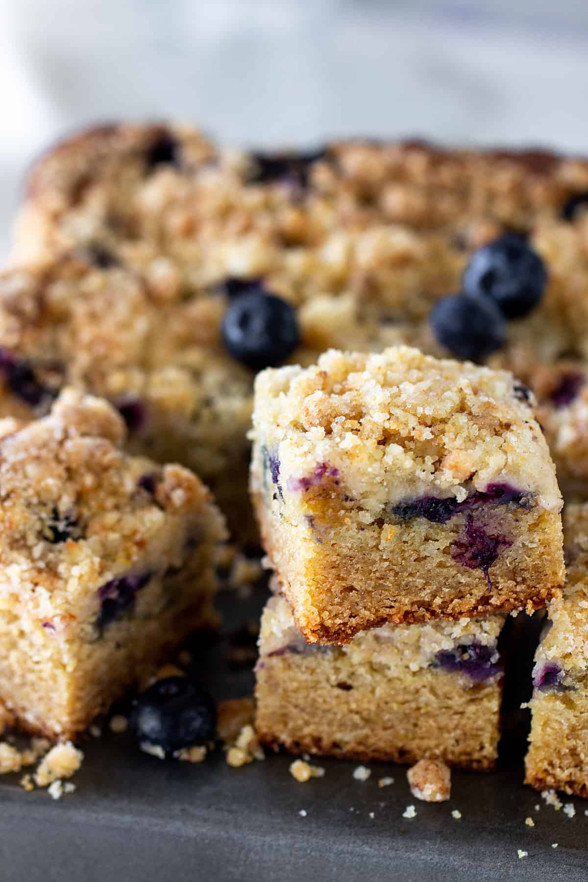 Squares of lemon cake with blueberries on metal surface, loose berries