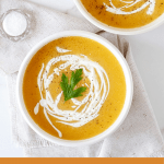 Two white bowls with pumpkin soup, spoons, salt, white background, pin with text