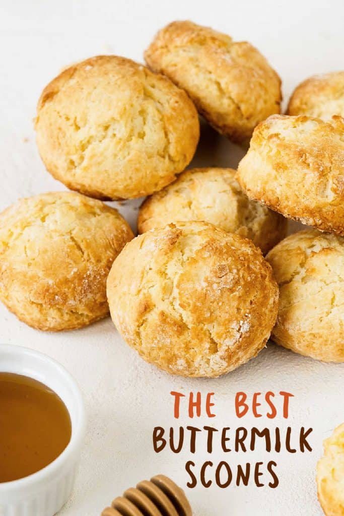 Pile of scones on a white surface, a honey bowl and brown text overlay.