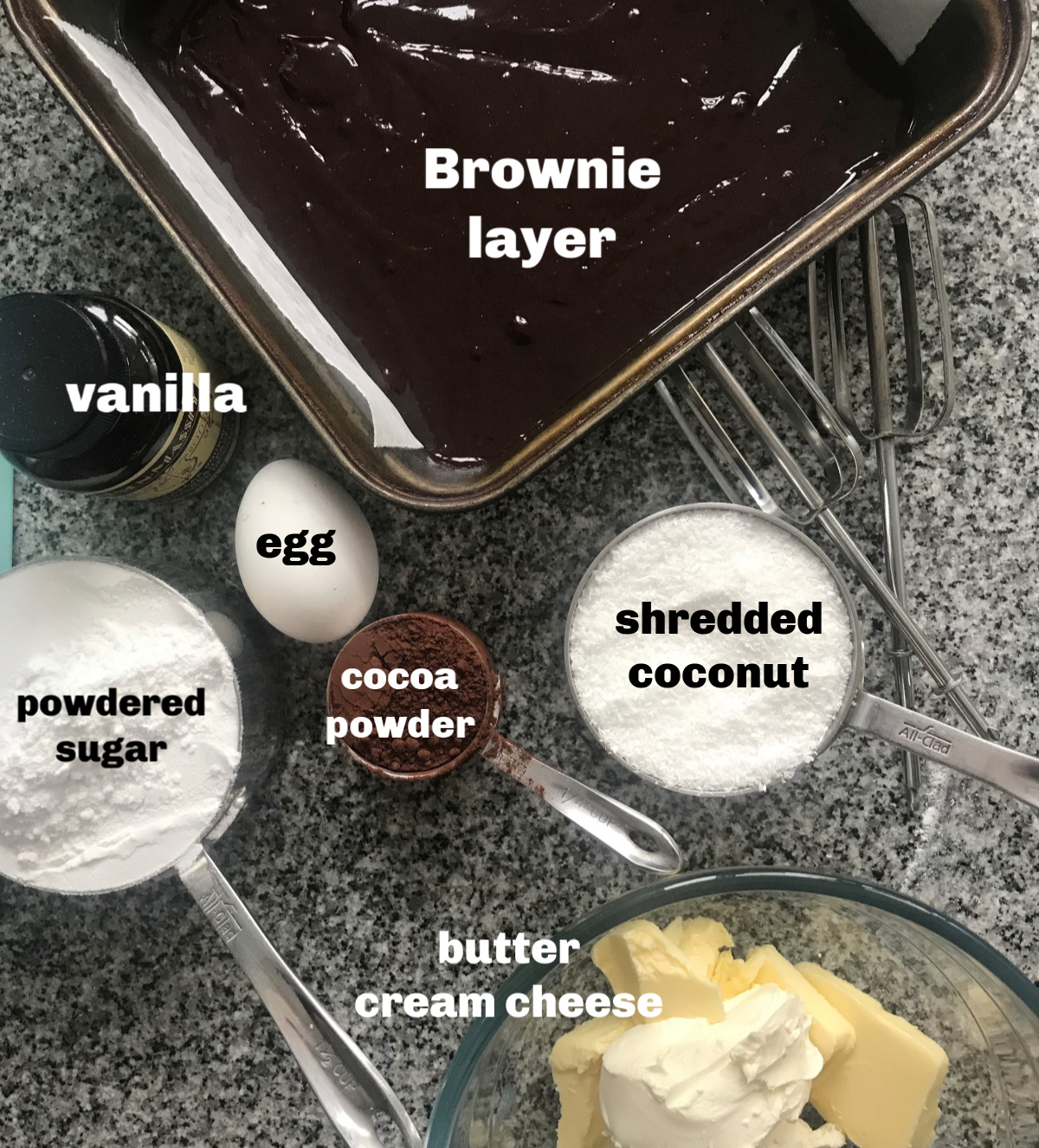 Square pan with brownie batter, cups and bowls with baking ingredients