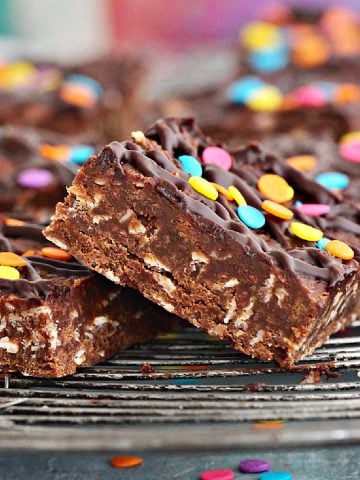 Close up of squares of chocolate no-bake oat bars with confetti on a wire rack.