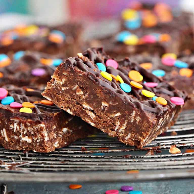 Close up of squares of chocolate no-bake oat bars with confetti on a wire rack.