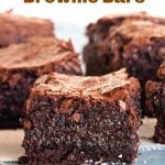 Squares of chocolate brownie on light blue surface, loose coconut around, image with text