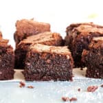 Several squares of brownie bars on a light blue surface. White background.
