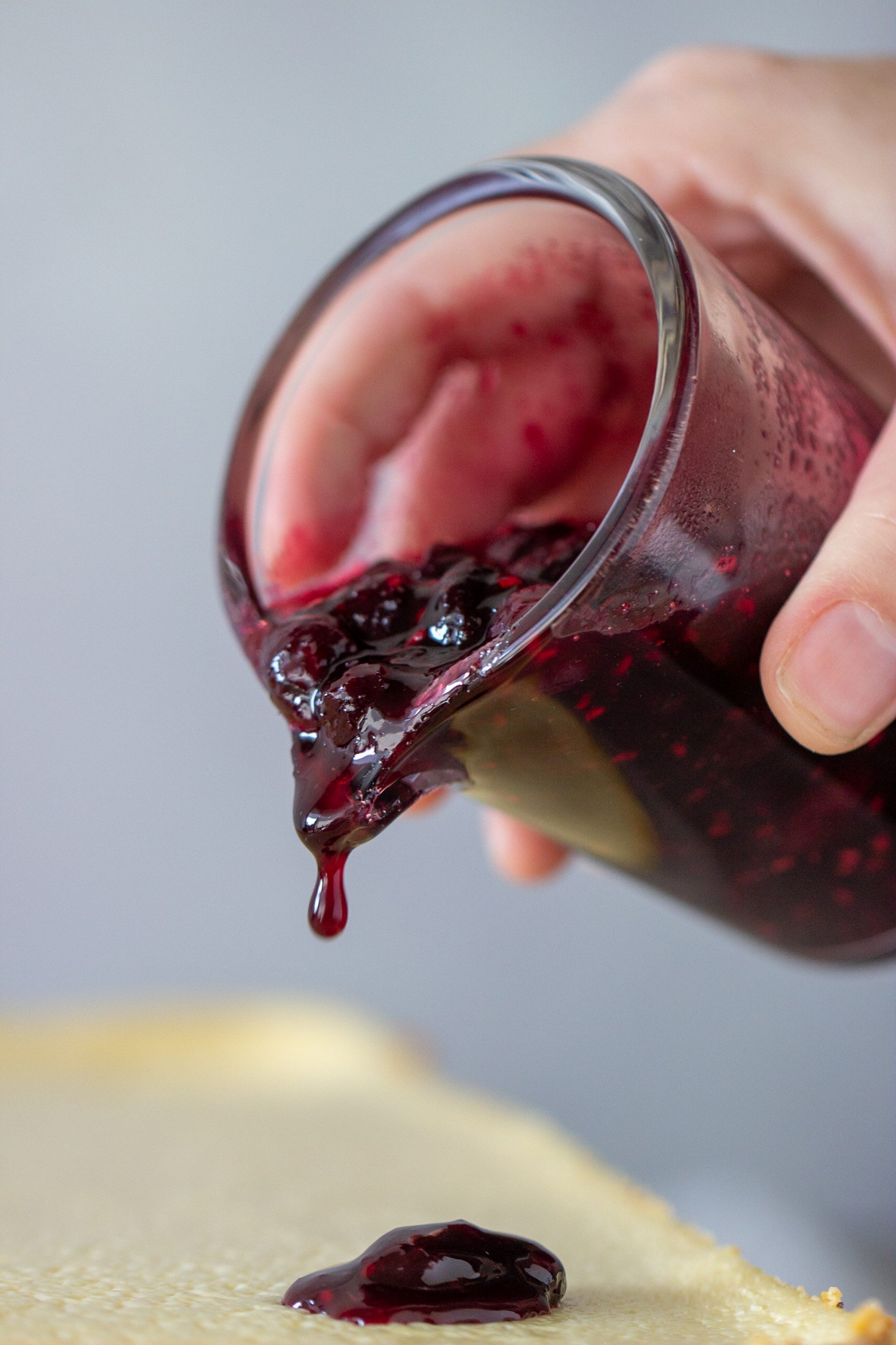 Hand pouring berry sauce from glass jar