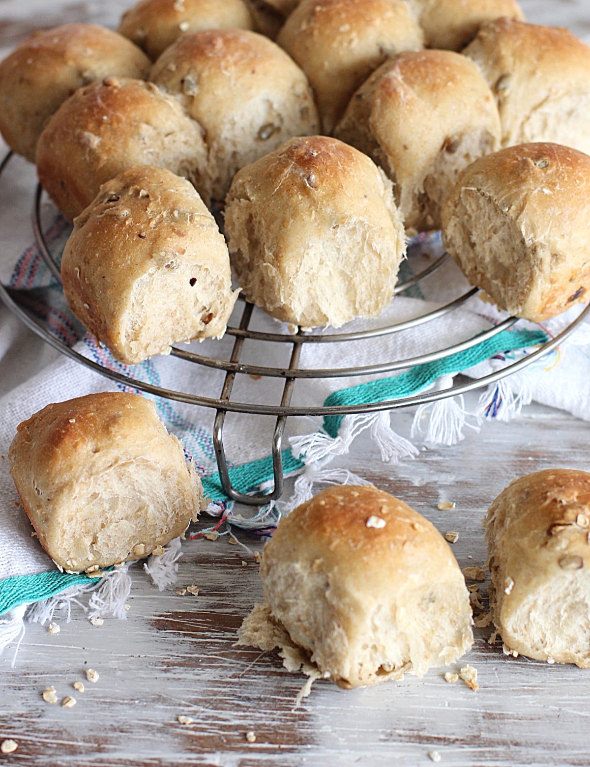 Dinner rolls on wire rack, white table, kitchen towel.