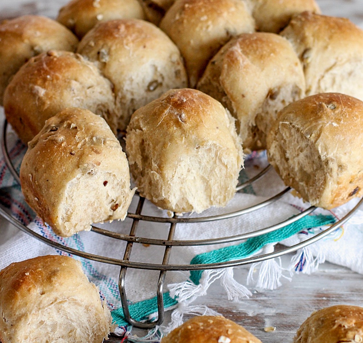 Bread rolls on a wire rack, kitchen towel below.