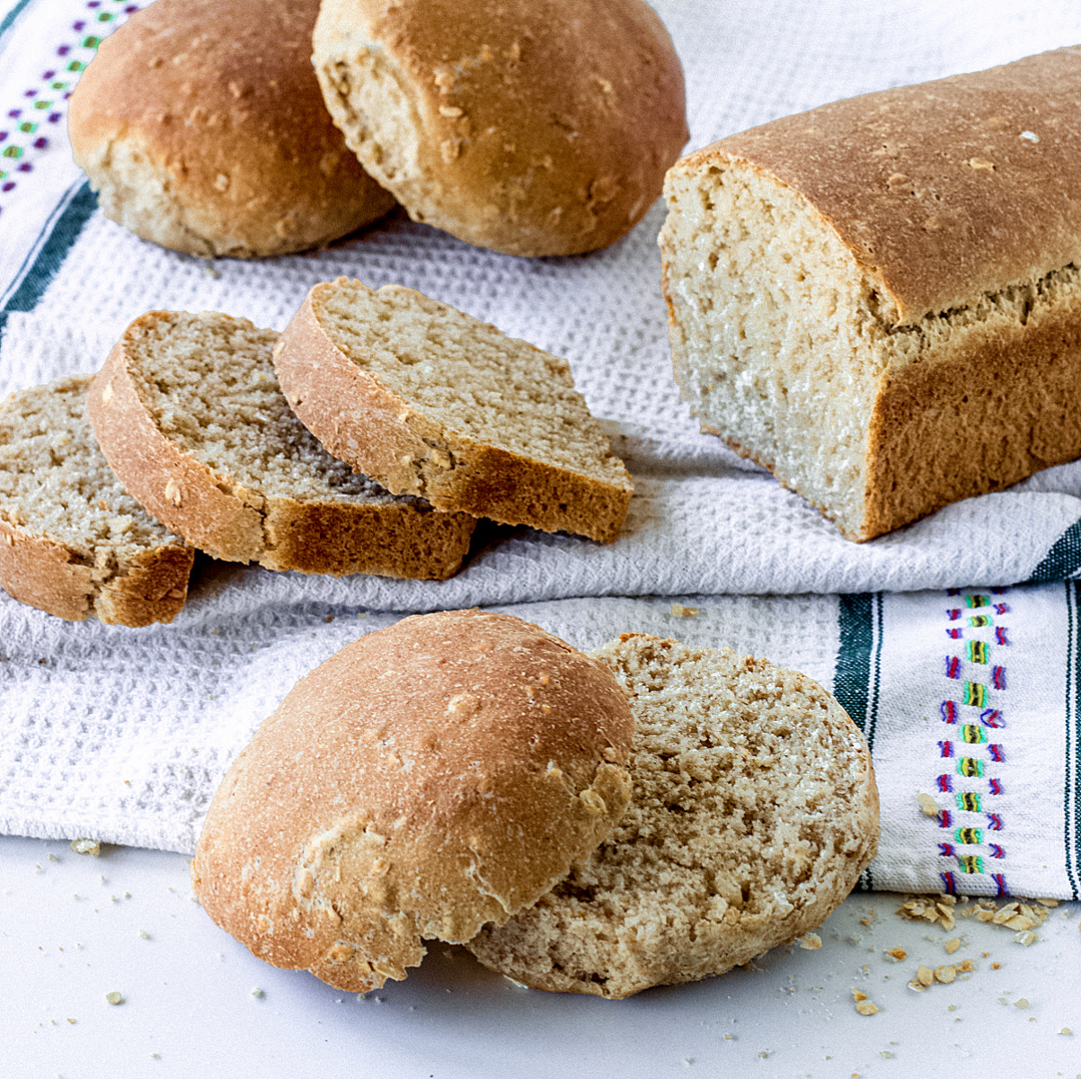 Loaf bread and buns on white kitchen towel, whole and sliced