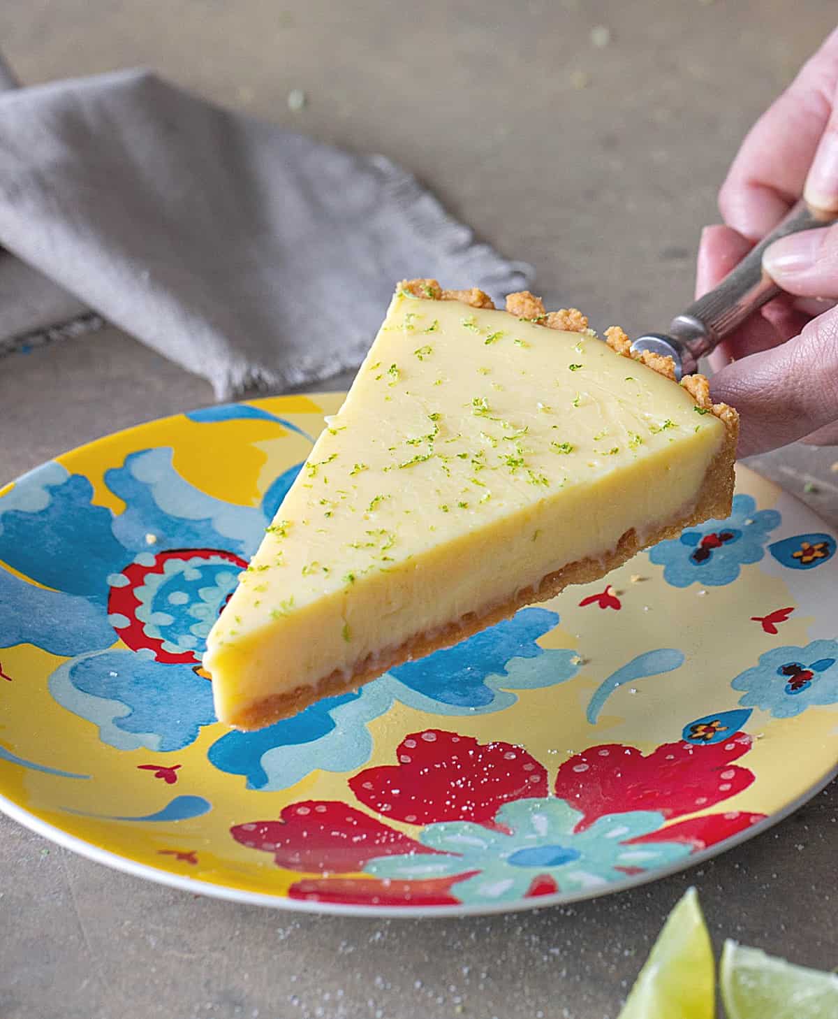 Serving a slice of lime pie on a colorful plate. Grey surface. 