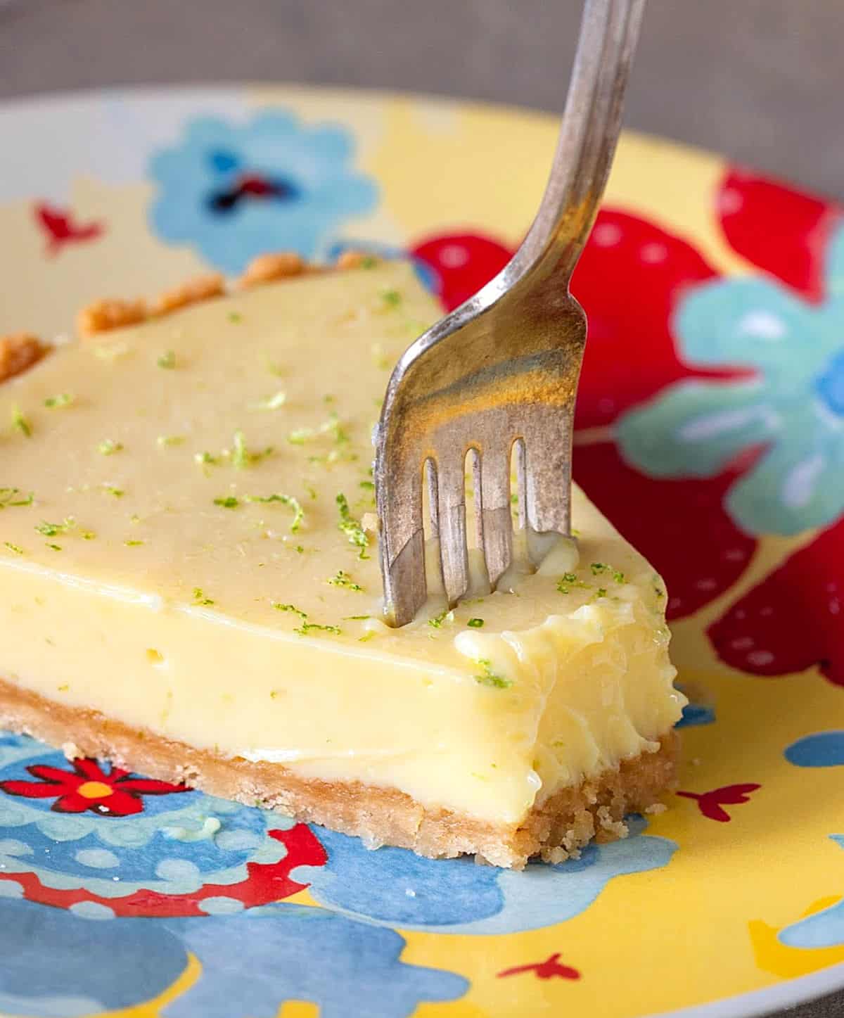 Slice of lime pie and silver fork on a colorful plate.