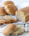 Loaf bread and buns on white kitchen towel, whole and sliced