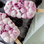 Overview of berry ice cream popsicles on metal pan with ice cubes; image with text