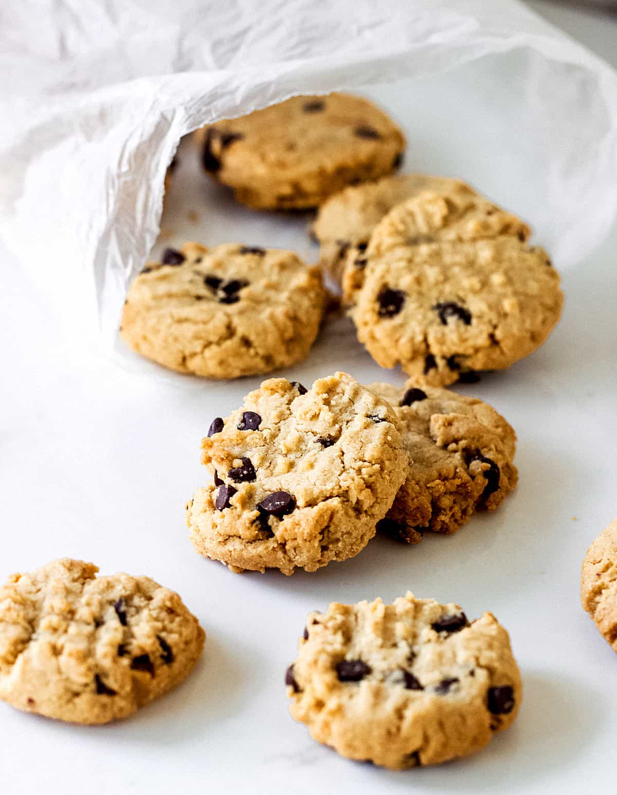 Round cookies with chocolate chips on a white table coming out from a plastic bag