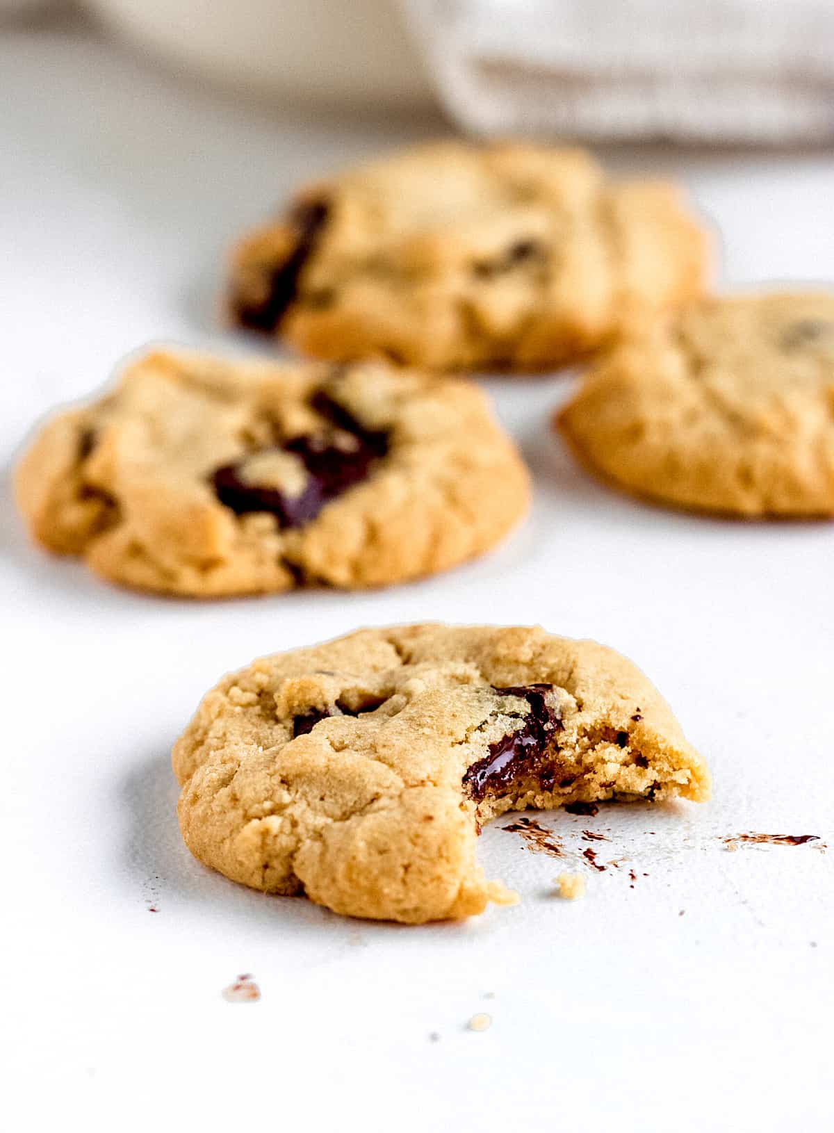 Cookies on white table, one is bitten, others are blurred in background