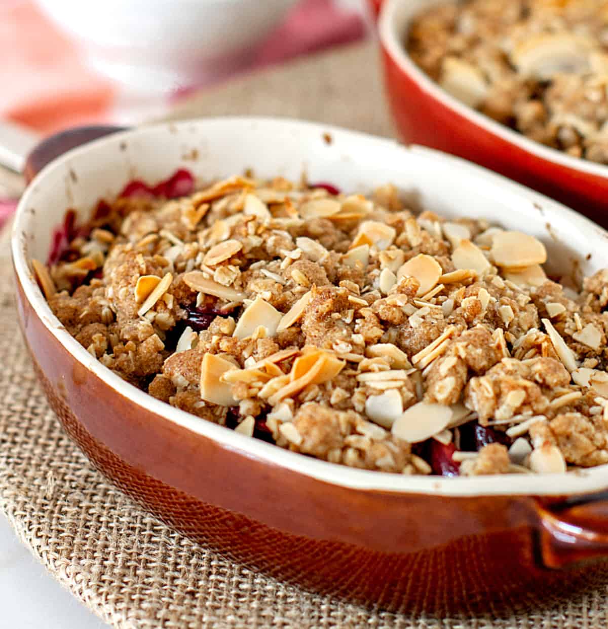 Brown oval dish with baked crumble, burlap surface.