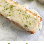 Partial view of glazed loaf cake on white marble surface