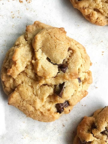 Flat top view of almond butter chocolate chunk cookies on white parchment paper.