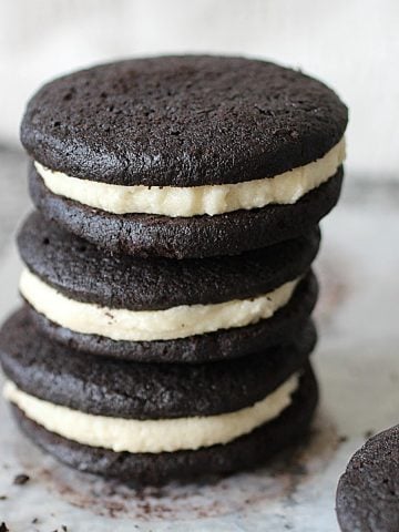 Three homemade oreo cookies stacked on a grey countertop