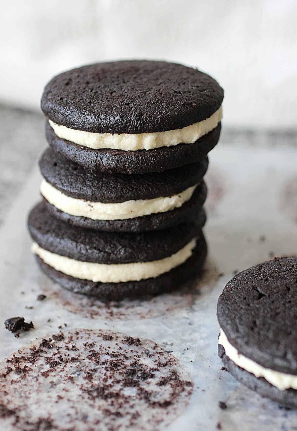 Grey counter with parchment paper and stack of stuffed homemade Oreos. 