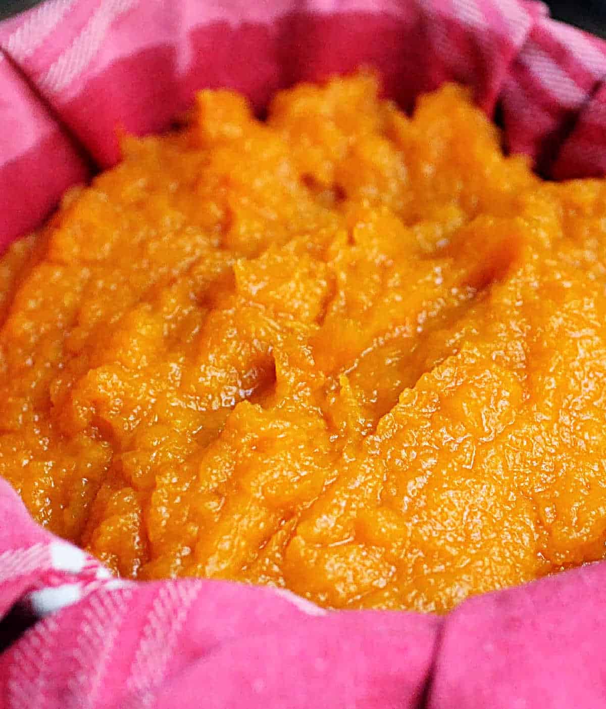 Draining pumpkin puree on a pink cloth. Close up image.