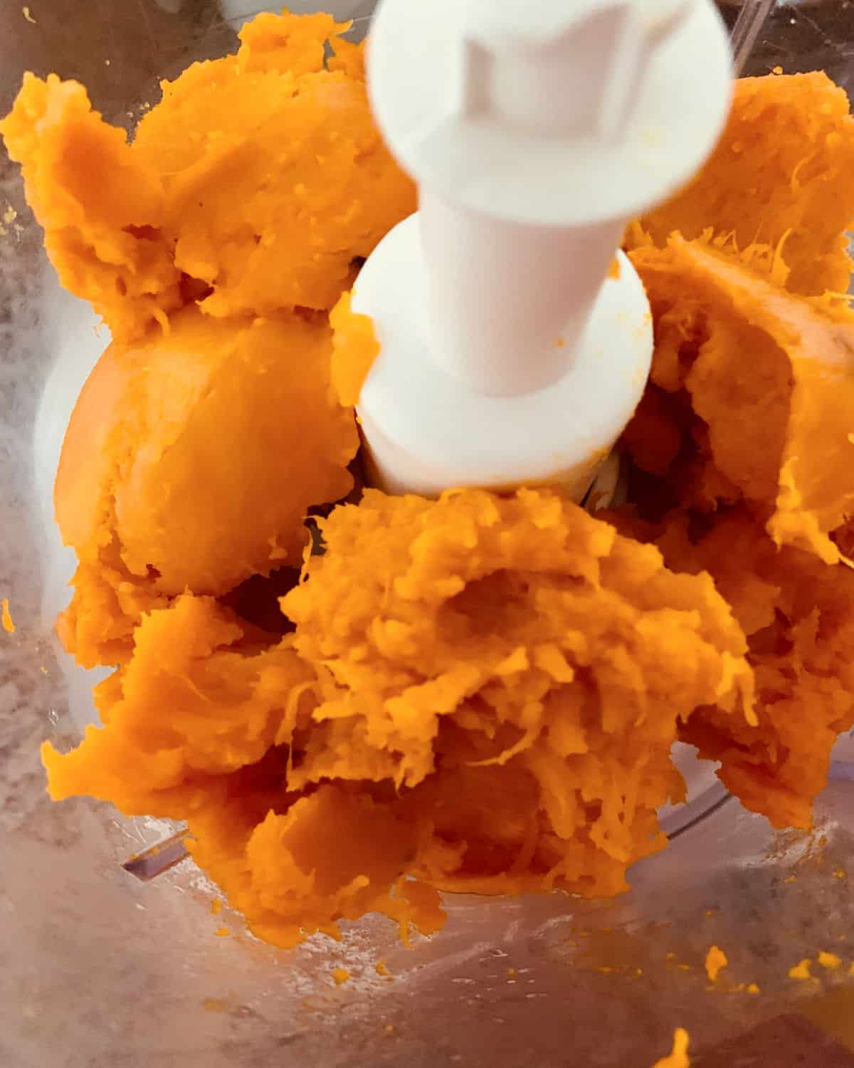 Chunks of baked pumpkin in the bowl of the food processor.