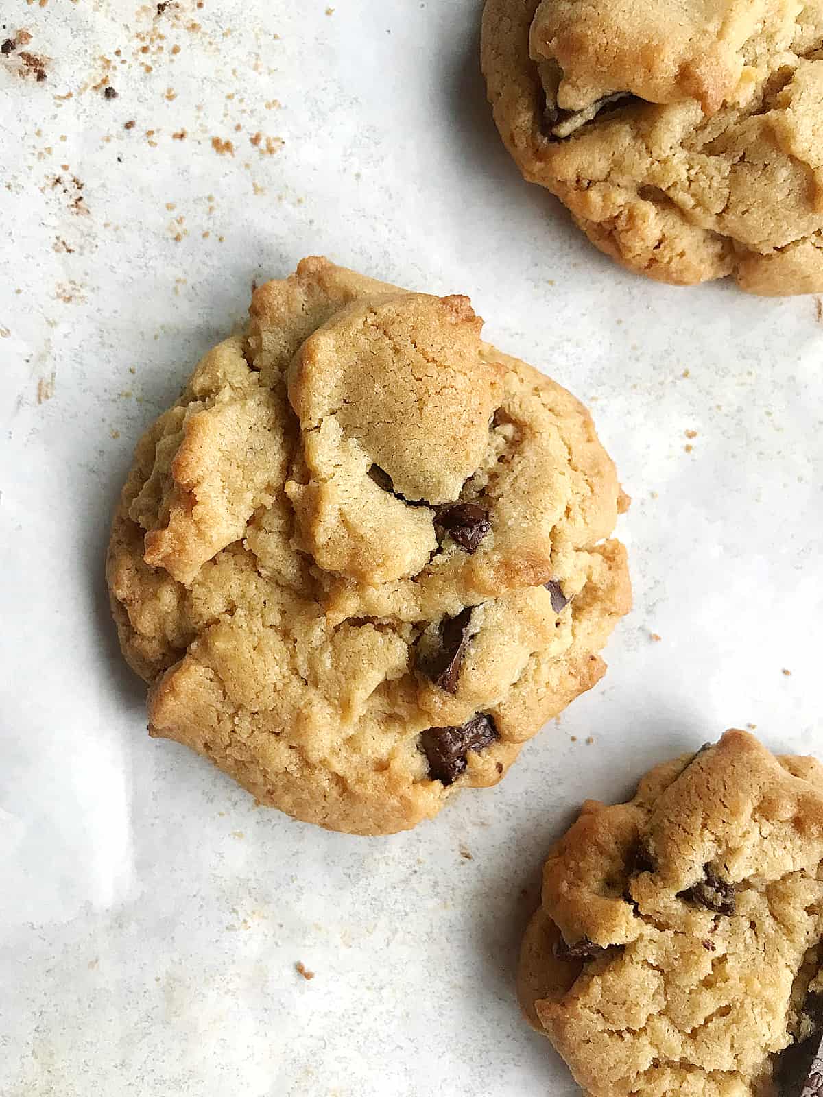 Close-up of single chocolate chunk cookie on parchment paper.