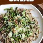 White plate of soba noodle salad with green beans, wooden table, image with text