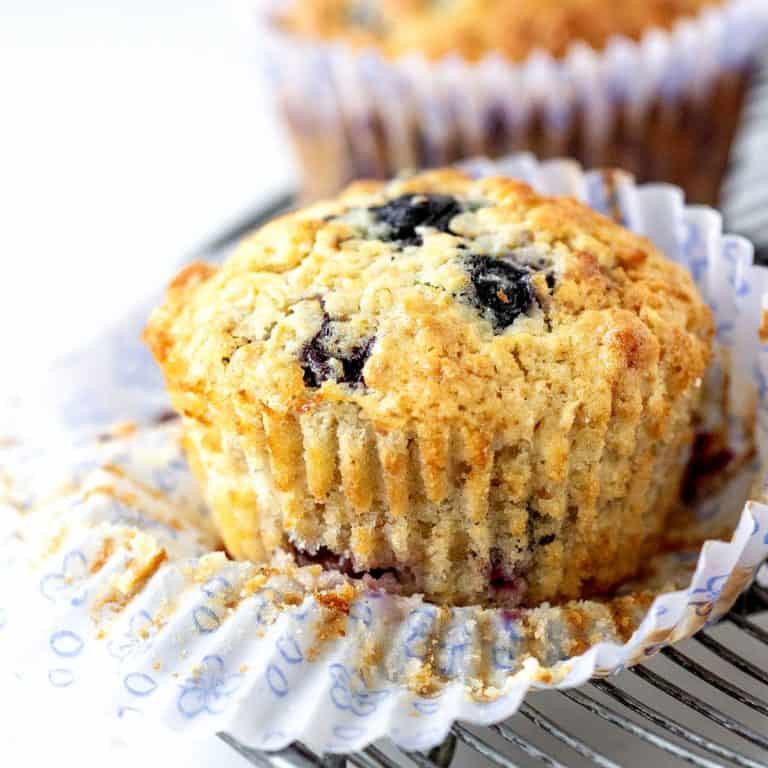 Opened paper liner with whole blueberry muffin.