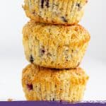 Stack of blueberry muffins, white background, image with purple and white text