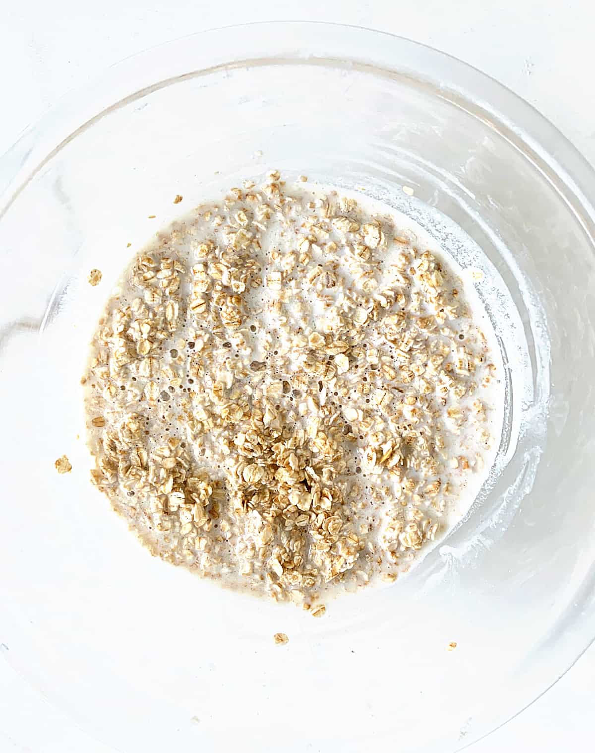 Oats and milk in a glass bowl on a white surface