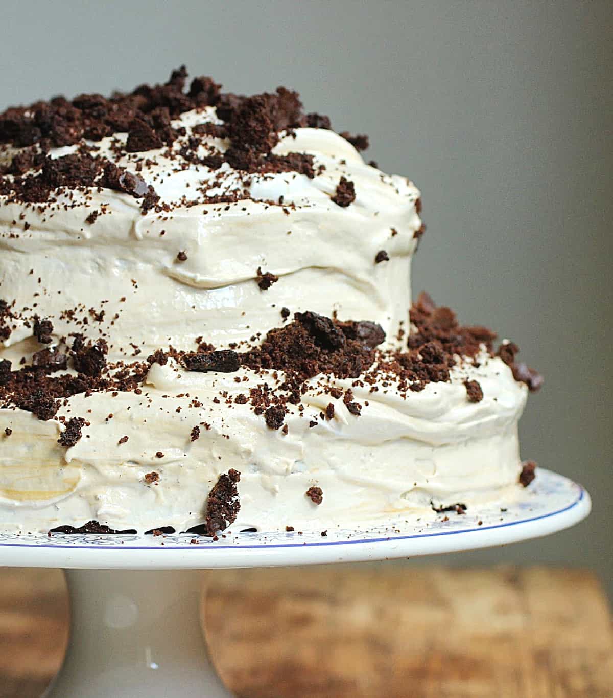 Partial view of whole cake on cake stand frosted with meringue and chocolate crumbs.