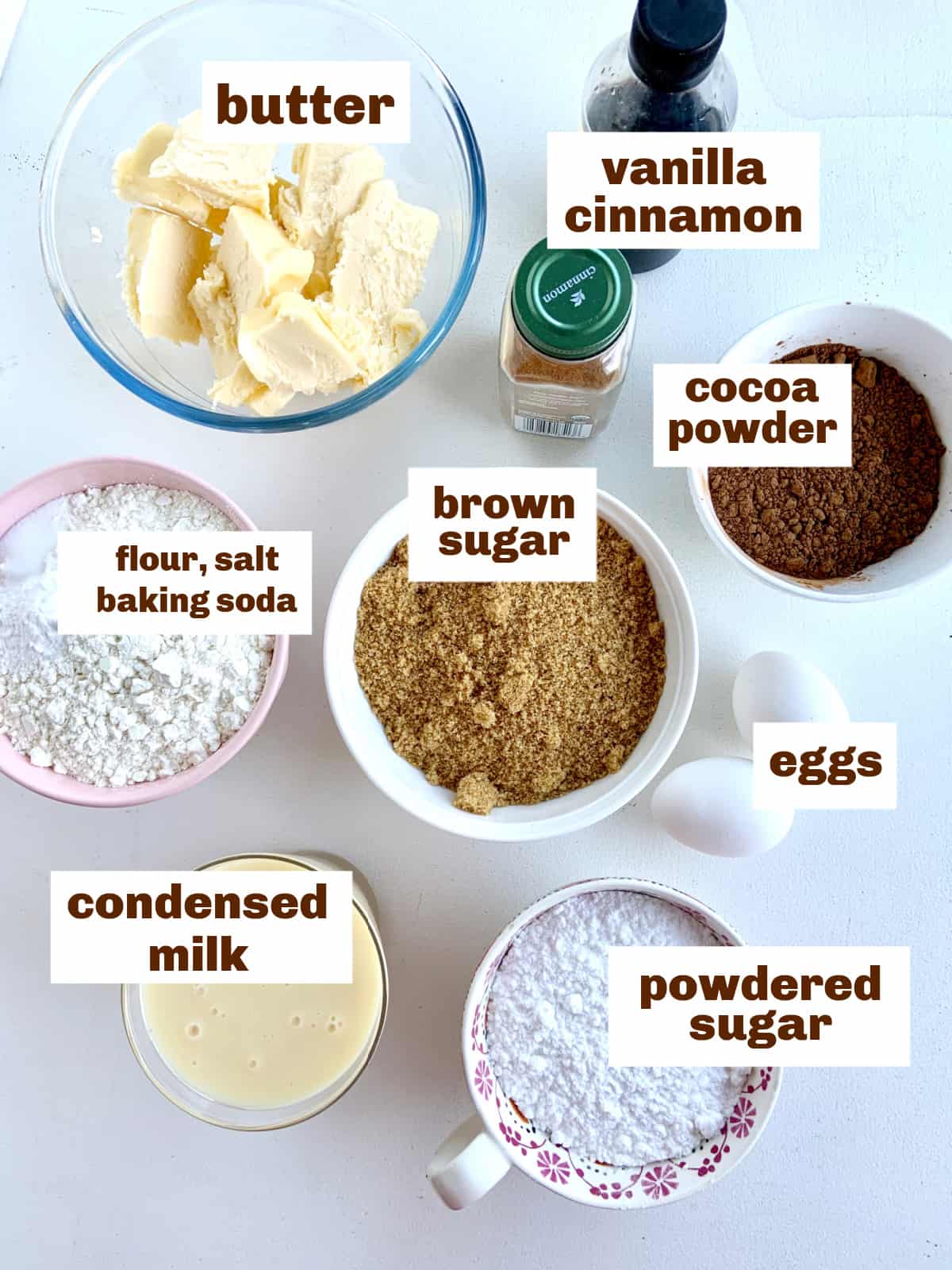 Bowls with chocolate cake ingredients on light colored surface, image with text
